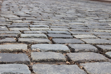 Road paved with cobblestones, close-up. Granite old paving stones, paved road. View of the old road in the city.の写真素材