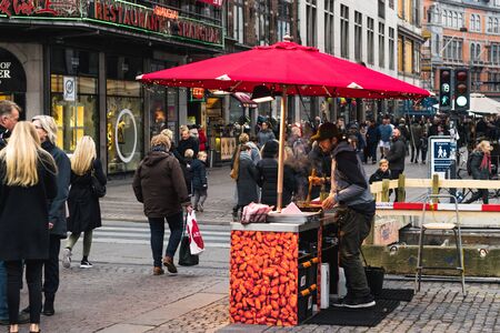 Copenhagen - October 17, 2016: On Nygade Street, a street merchant is frying some nuts for selling...