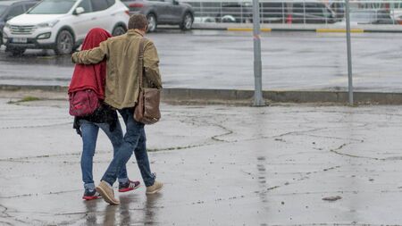 CHISINAU, MOLDOVA - 13 MAY, 2016: A boy and a girl passing through a rain shower in Chisinau.のeditorial素材