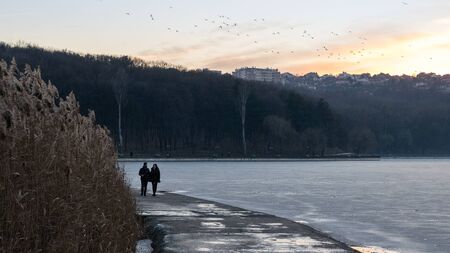CHISINAU, MOLDOVA - 26 DECEMBER, 2016: A couple walking nearby a frozen lake.のeditorial素材