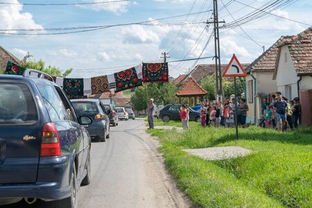 TRANSYLVANIA REGION, ROMANIA - 10 JUNE, 2017: Romanian wedding tradition. Locals allowing cars to pass after groom and bride pays a symbolic sum of money.のeditorial素材