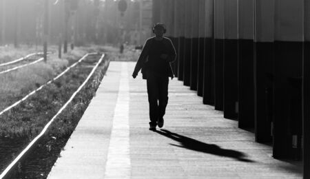CLUJ-NAPOCA, ROMANIA - 11 AUGUST 2018: Man walking and lisining music at railway station in the morning in Cluj-Napoca, Romania.のeditorial素材