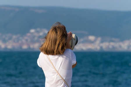 An unidentified girl looking through a tower viewer at sea in Nessebar, Bulgaria. A girl looking through a coin binocular, free use viewer, outdoor viewer.の写真素材