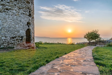 Sun rising from the sea on the Black Sea Coast. Alley at sunrise in Nessebar ancient city with ancient Tower at the left.の写真素材
