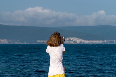 An unidentified girl looking through a tower viewer at sea in Nessebar, Bulgaria. A girl looking through a coin binocular, free use viewer, outdoor viewer.の写真素材