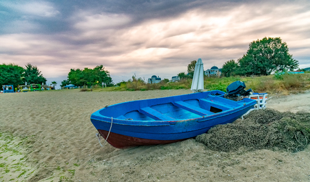 A blue boat and fishing net at sunset on a beach in Sunny Beach on the Black Sea coast of Bulgaria.の写真素材