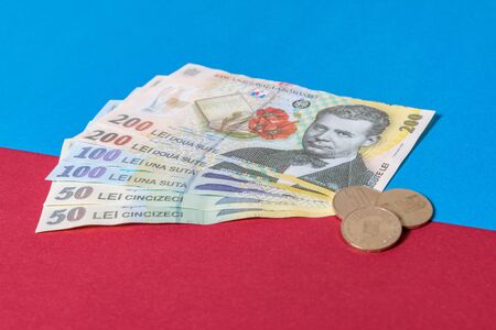 Romanian banknotes and coins on a blue and red background. Coloseup of RON, Romanian Currency. Romanian RON, Lei Banknotes issued by BNR, National Bank of Romania. Romania Finance and economy concept.の写真素材