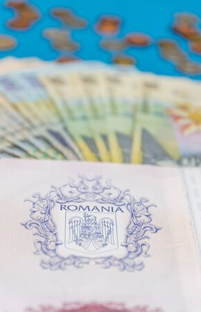 Romanian concept. The Romanian passport and Romanian banknotes/coins on a blue and red background. Coloseup of Romanian Passport and Romanian currency. Romania Finance and economy concept.の写真素材