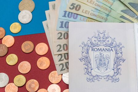 Romanian concept. The Romanian passport and Romanian banknotes/coins on a blue and red background. Coloseup of Romanian Passport and Romanian currency. Romania Finance and economy concept.の写真素材