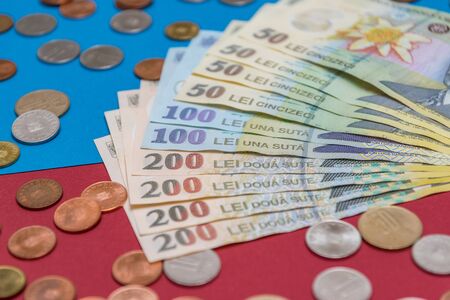 Romanian banknotes and coins on a blue and red background. Coloseup of RON, Romanian Currency. Romanian RON, Lei Banknotes issued by BNR, National Bank of Romania. Romania Finance and economy concept.の写真素材