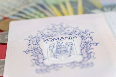 Romanian concept. The Romanian passport and Romanian banknotes/coins on a blue and red background. Coloseup of Romanian Passport and Romanian currency. Romania Finance and economy concept.の写真素材