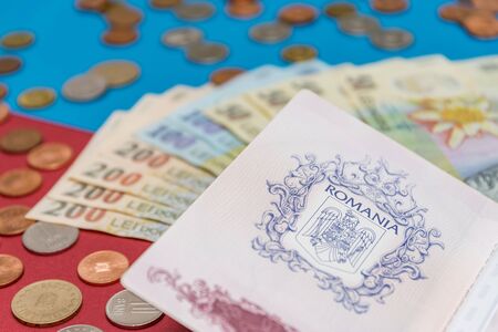 Romanian concept. The Romanian passport and Romanian banknotes/coins on a blue and red background....