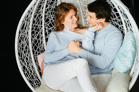 Couple girl and guy hugging on a big chair.