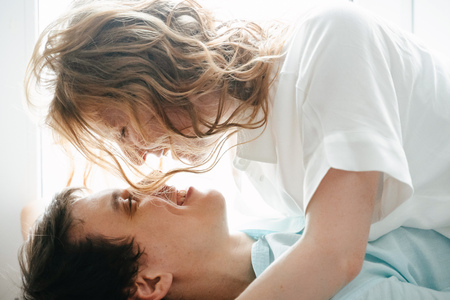 Happy girl and man hugging near window in home.の写真素材