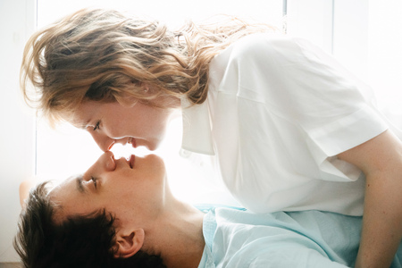 Happy girl and man hugging near window in home.の写真素材