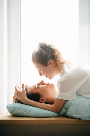 Happy girl and man hugging near window in home.の写真素材