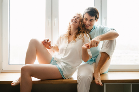 Happy girl and man hugging near window in home.の写真素材