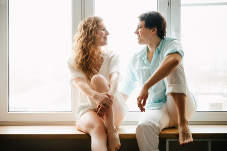 Happy girl and man hugging near window in home.の写真素材
