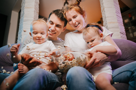 Young family with children eating popcorn on the couch.の写真素材