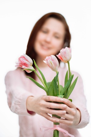Young beautiful woman gives pink tulips on white background.の写真素材