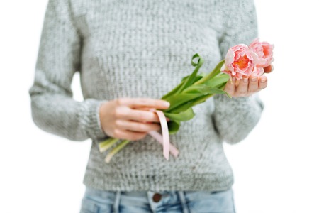 Young woman holding pink tulips on a white background.の写真素材