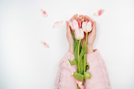 Young girl holding a bouquet of pink tulips. Top view, white background.の写真素材