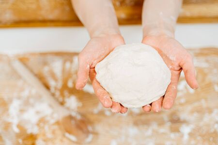 Woman hands holding a raw dough on wood tableの写真素材