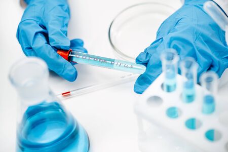 scientist in protective gloves holds tube with liquid and written word covid-19