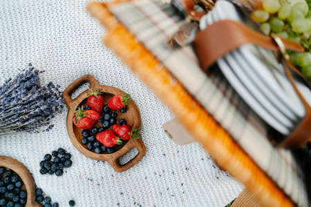 Healthy tasty fruits strawberries and blueberries in a wooden plate on a knitted blanket.の写真素材