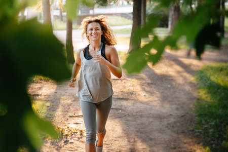 A slender European athlete is engaged in fitness jogging in the park. Healthy lifestyle.の写真素材