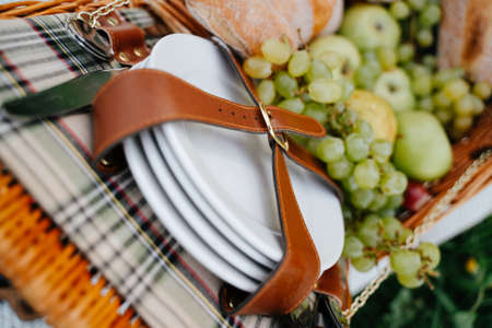 Close-up of a leather strap holding ceramic white picnic plates with fruits.の写真素材