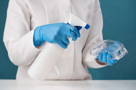 Spraying a chemical solution from a white dispenser to kill harmful bacteria and viruses. Disinfection of glasses by a health worker.の写真素材