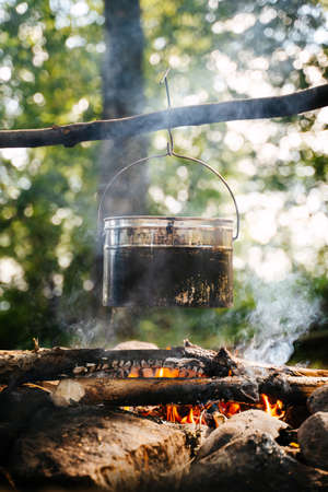Aluminum utensils for cooking over a fire in the forest. Vertical shot.
