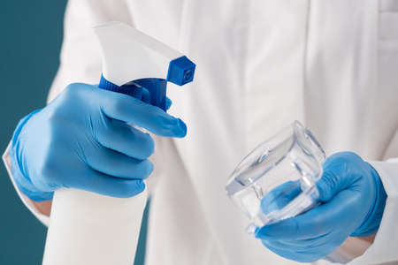 Close-up focus on a white spray bottle in the hands of a paramedic, for treating an infected medical device with a disinfectant. Horizontal.の写真素材