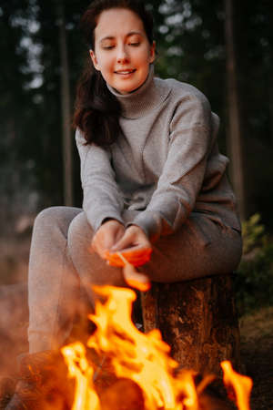 Camping in nature. A woman is on a hike to cook sausages on a campfire. Concept of hiking and outdoor recreation.の写真素材