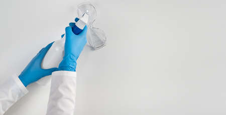 An overhead view of a hand in latex gloves holding a nebulizer to handle a medical device after an infected patient. Copy space. White background.の写真素材