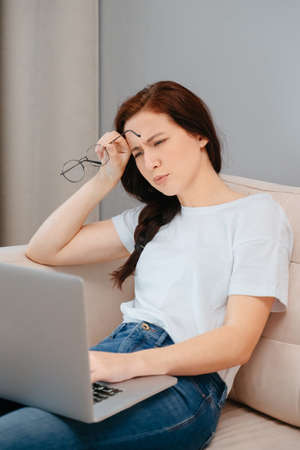 Young woman is carefully studying the information on a laptop while sitting at home.の写真素材