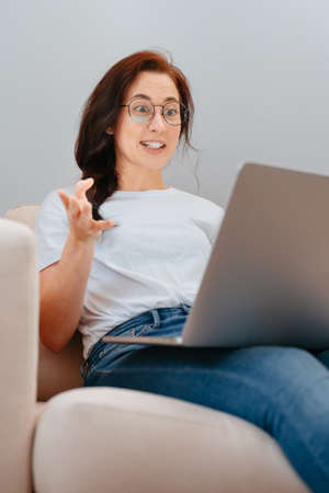 Young woman communicates emotionally with gestures via video communication with friends.の写真素材
