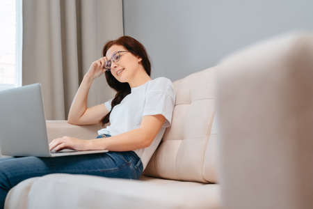 Young woman is looking for useful information on the Internet through a laptop while sitting at home.の写真素材