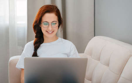 Woman smiling communicates online through a laptop in home setting. Concept online orders and training.の写真素材