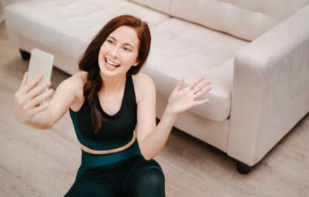 Young athlete coach is welcomed by fitness students online via the phone.Concept of online learning and sports.の写真素材