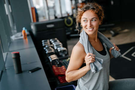 Happy woman after an intense workout in the gym is resting with towel. Concept of fitness and a healthy lifestyleの写真素材