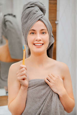 Portrait of a smiling women with an eco toothbrush in the bathroom. Oral and dental care.の写真素材