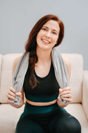 Portrait of a woman in sportswear with a towel after an intensive workout at home.Concept of health and fitness.の写真素材