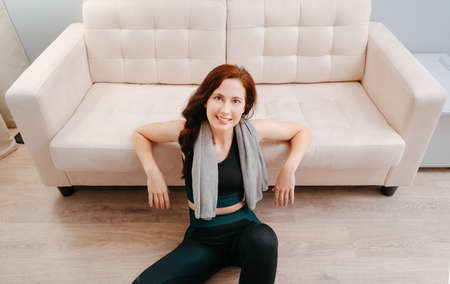 Woman is smiling in sports clothes sitting on the floor top view to relax after doing sports at home.Concept of weight loss.の写真素材