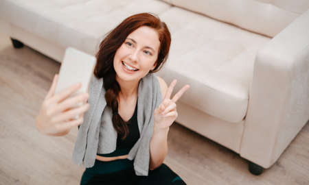 Young athletic slender female yoga coach records a video of an online workout.Concept of home fitness.の写真素材