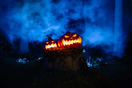 Pumpkin lanterns with Jacks carved faces on the traditional horror festival in the forest with smoke.の写真素材