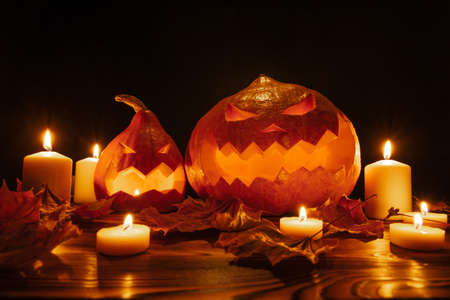 Pumpkin lanterns on a black background for Halloween with carved scary faces with candles. Concept of a horror holiday.の写真素材