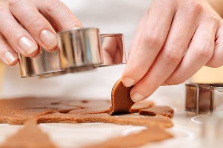 A woman cutting gingerbread dough men with a Christmas cookie cutter close-up.の写真素材