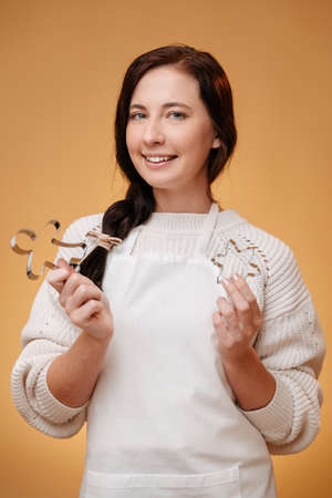 Woman pastry chef in white apron with metal baking pan on yellow background. Concept of christmas cookies.の写真素材